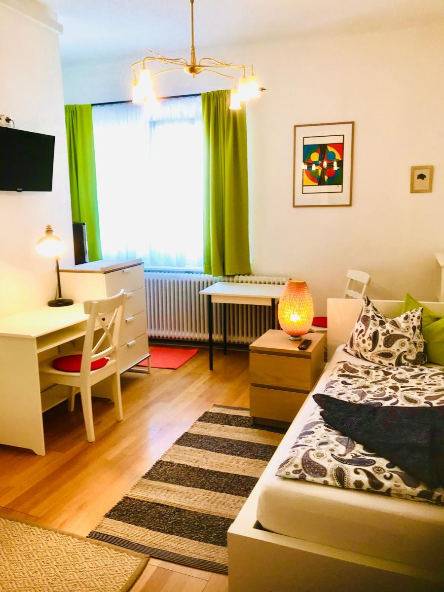 Modern möbliertes Zimmer mit Schreibtisch, Sofa und Kunst an der Wand